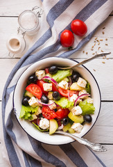 Delicious greek salad with feta cheese and olives in a white bowl