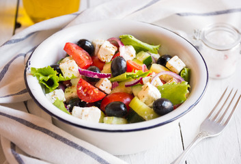 Delicious greek salad with feta cheese and olives in a white bowl