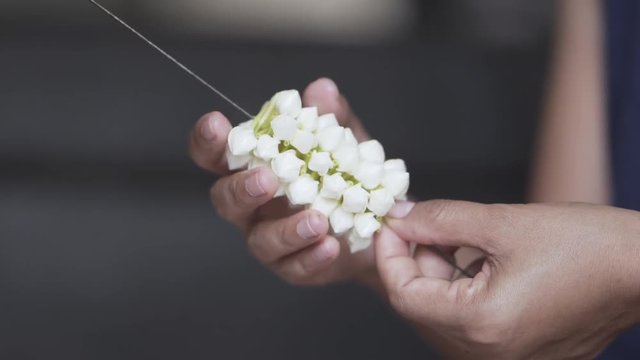 Slow motion, The hands of the young woman are making beautiful garlands of white gardenia flowers.