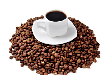white cup of coffee on a white saucer stands on a hill of coffee beans on a white background  angle view from above