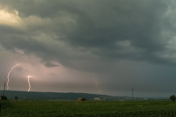 Several lightning bolts strike down in the foothills of the Carpathian mountains, Romania during an evening thunderstorm