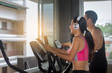 beautiful Asian woman is exercising in a gym with a personal trainer, a handsome man. Fitness concept for health