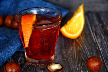 red liqueur on a wooden surface with macadas and orange slices