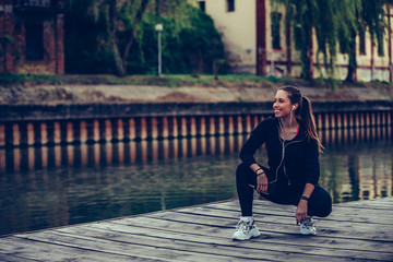 Young woman taking break after jogging  by the river