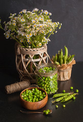 Beautiful summer still life with green peas and wildflowers on a black wooden table