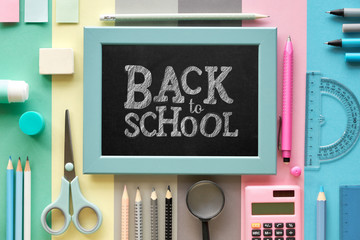 Stationary items on pastel color paper background, text "Back to school" on the chalk board