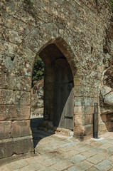 Fototapeta na wymiar Open gateway with wooden door on a stone wall