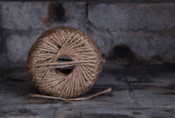 Close-up of  a large ball of brown fibrous string with high definition detail shown end-on set in a stone fireplace background swith copy space