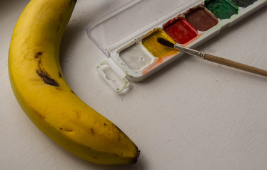 a banana watercolor paint and brush on white background