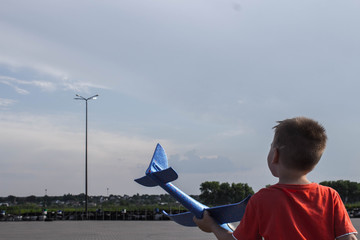a boy playing with a airplane in the street
