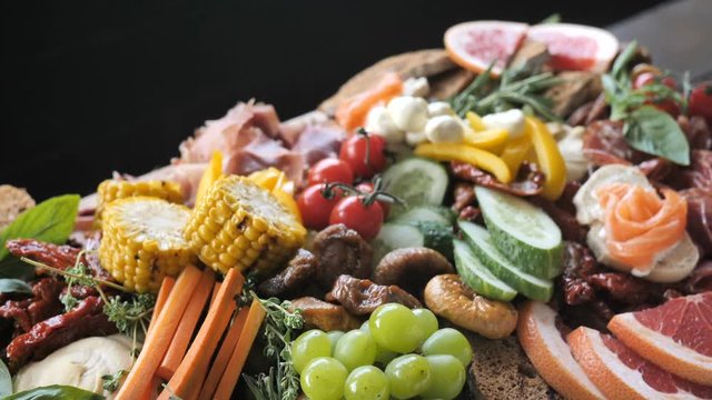 Assorted Ham, Sausage, Mozzarella, Grapefruit, Grapefruit, Date, Basil, Cucumber, Vegetable Grill on a wooden board for a Buffet in a restaurant or event 4k