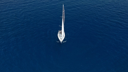 Aerial photo of sail boat cruising open ocean deep blue sea