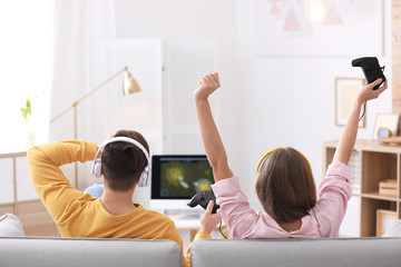Emotional young couple playing video games at home