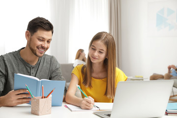 Fototapeta na wymiar Father helping his teenager daughter with homework indoors
