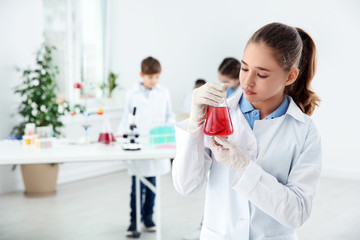 Schoolgirl holding conical flask at chemistry class