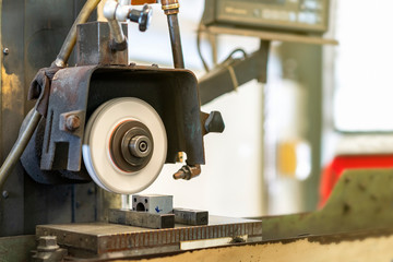 Close up cutting or grinding wheel during rotating or working with product on high accuracy and automatic surface horizontal grinding machine for finishing process in industrial metal work at factory