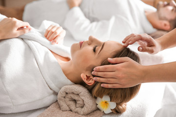 Obraz na płótnie Canvas Young woman enjoying head massage in spa salon
