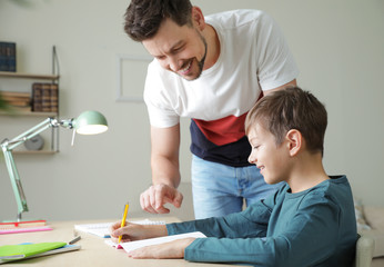 Fototapeta premium Dad helping his son with school assignment at home