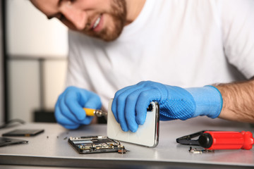 Technician repairing mobile phone at table in workshop, closeup
