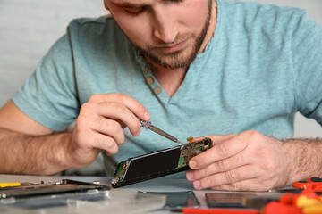 Technician repairing mobile phone at table, closeup