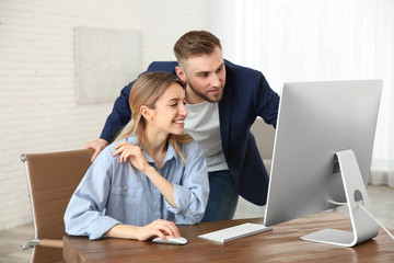 Man helping his colleague work with computer in office