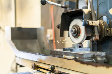 Close up cutting or grinding wheel during rotating or working with product on high accuracy and automatic surface horizontal grinding machine for finishing process in industrial metal work at factory