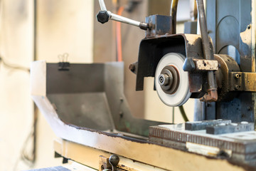 Close up cutting or grinding wheel during rotating or working with product on high accuracy and automatic surface horizontal grinding machine for finishing process in industrial metal work at factory