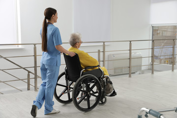 Fototapeta na wymiar Nurse assisting senior woman in wheelchair at hospital