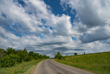 Fototapeta premium rural, landscape, distance, expanse, terrain, meadows, herbs, trees, meadow, flowers, plants, flora, blue, sky, white, clouds, road, turn, beauty