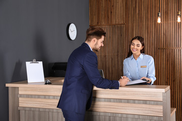 Receptionist registering client at desk in lobby