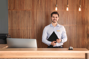 Portrait of receptionist with clipboard at desk in lobby
