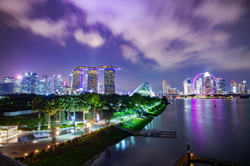 Fototapeta premium SINGAPORE, SINGAPORE - MARCH 2019: Vibrant Singapore skyline with Marina Bay Sands, Gardens by the bay with cloud forest, flower dome and supertrees at sunset. Top view from marina barrage