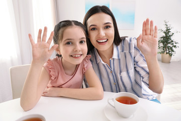Mother and daughter using video chat at table indoors, view from camera perspective