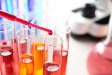 Dripping reagent into test tube with sample in chemistry laboratory, closeup. Space for text