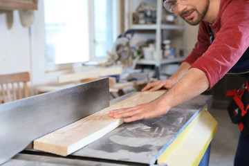 Mature man using wood working machine at carpentry shop