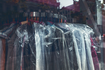 clothes wrapped with plastic on a rack in the window of a laundry