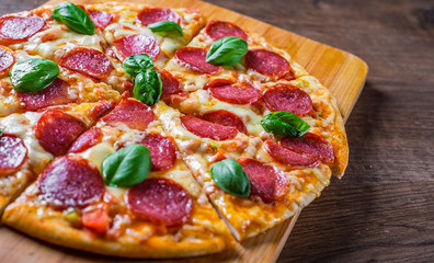 Pepperoni Pizza with Mozzarella cheese, salami, Tomato sauce, pepper, Spices and Fresh basil. Italian pizza on wooden table background