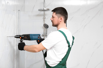 Handyman working with drill in bathroom. Professional construction tools