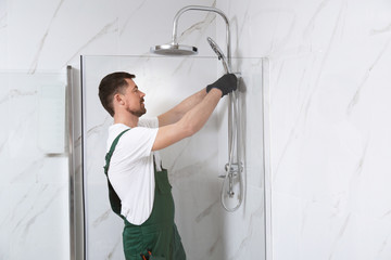 Professional handyman working in shower booth indoors