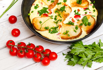 Rustic omelette breakfast with tomatoes and parsley on white rustical background