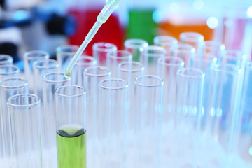 Dripping reagent into test tube with sample in chemistry laboratory, closeup