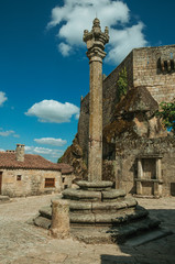 Close-up of stone pillory and gothic house on square