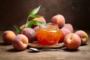 glass jar of peach jam with fresh fruits