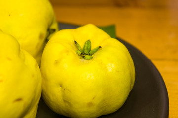 large yellow quince fruits on a ceramic plate, with anise, cinnamon, and walnuts