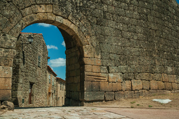 Old house seen through arch gate from a stone wall