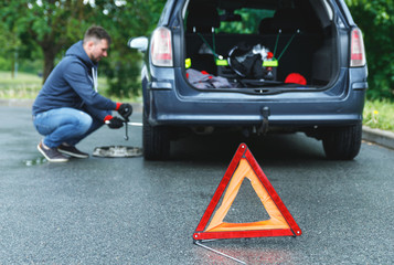  Warning triangle and man changing car wheel