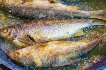 fried river fish with crispy crust in a frying pan, homemade dish, close up
