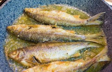 fried river fish with crispy crust in a frying pan, homemade dish, close up