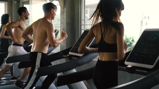 Row of Caucasian people exercising on treadmills at modern gym. Fitness men and women working out together