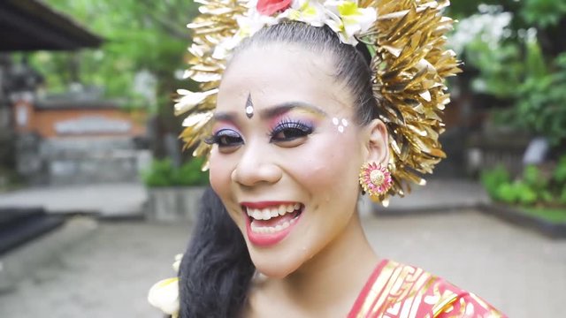 Pretty balinese dancer smiling and looking at the camera in the temple